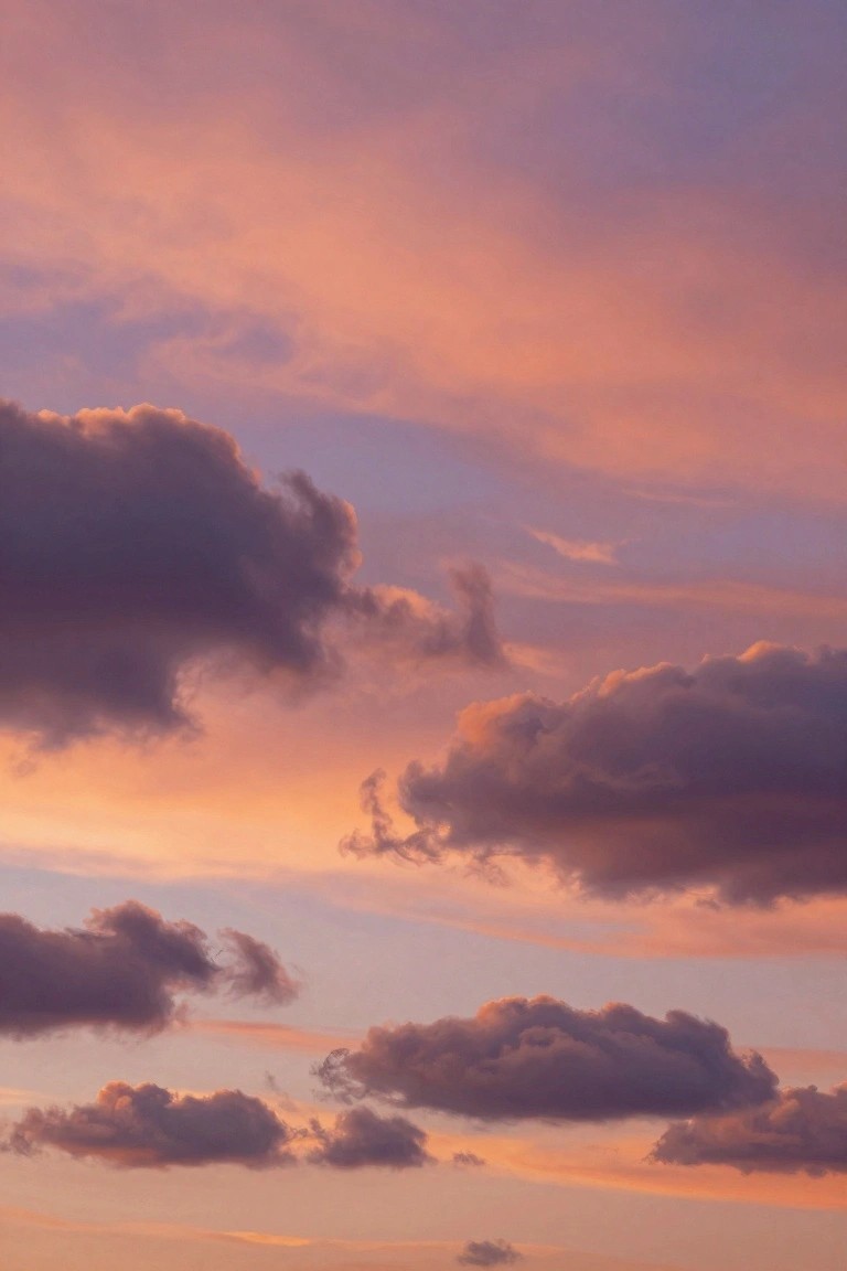 Dark clouds drifting across a vibrant pink and orange sunset sky.