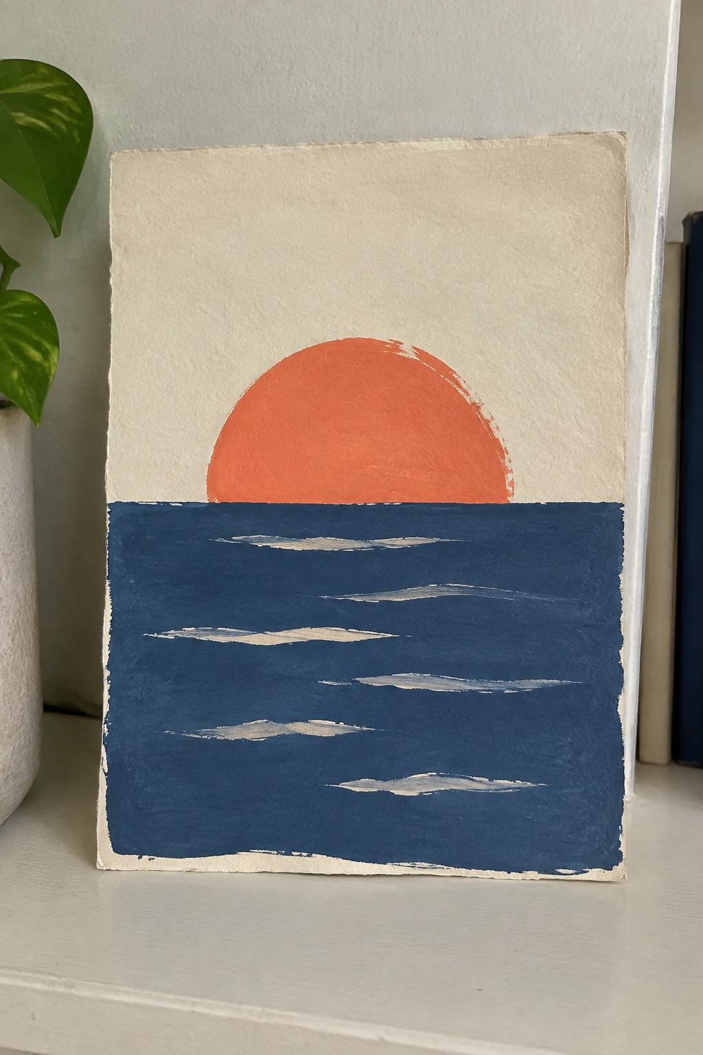 Minimalist painting of orange sun over dark blue sea with white wave lines