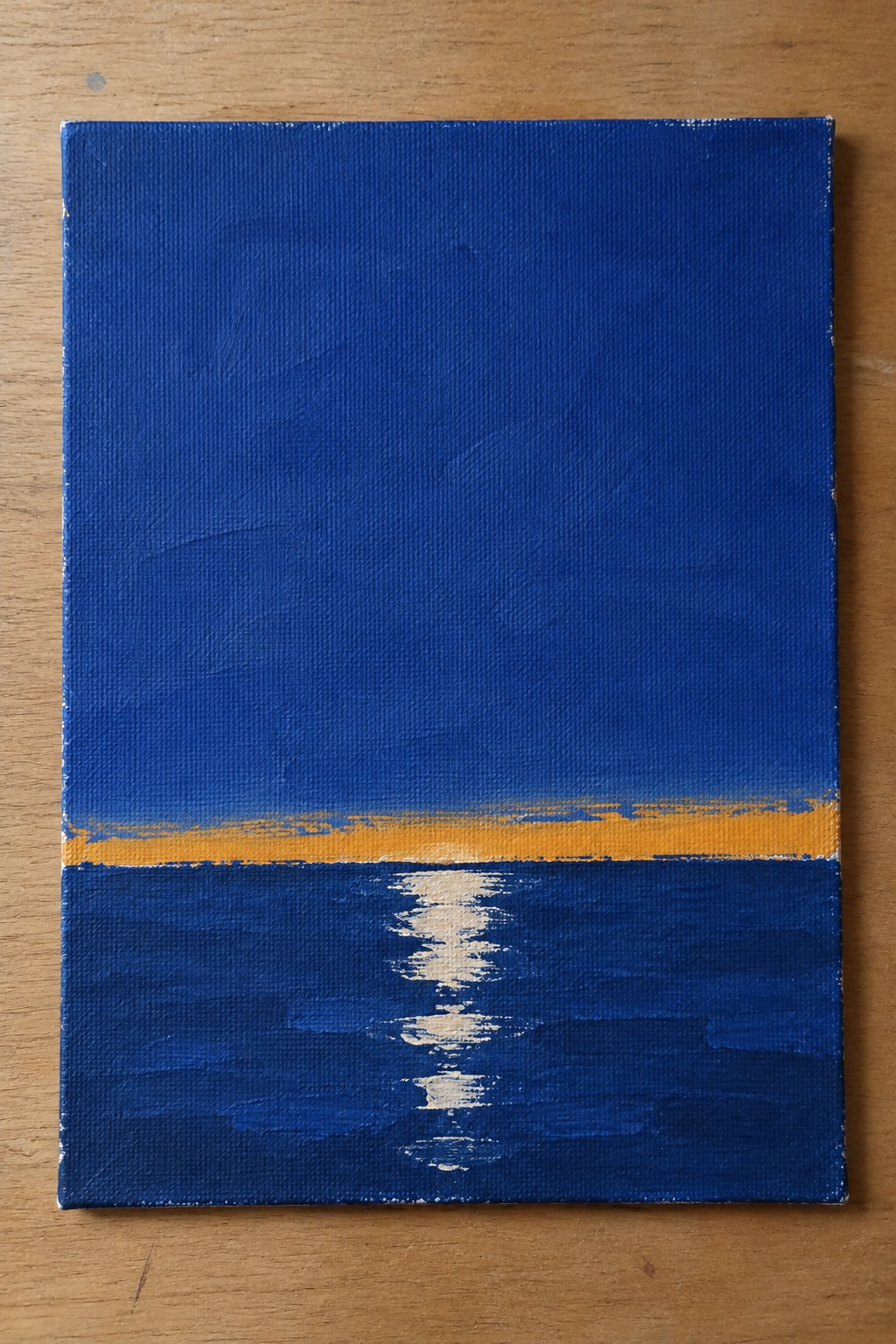 Abstract painting of blue sea with yellow horizon stripe and white water reflection on canvas