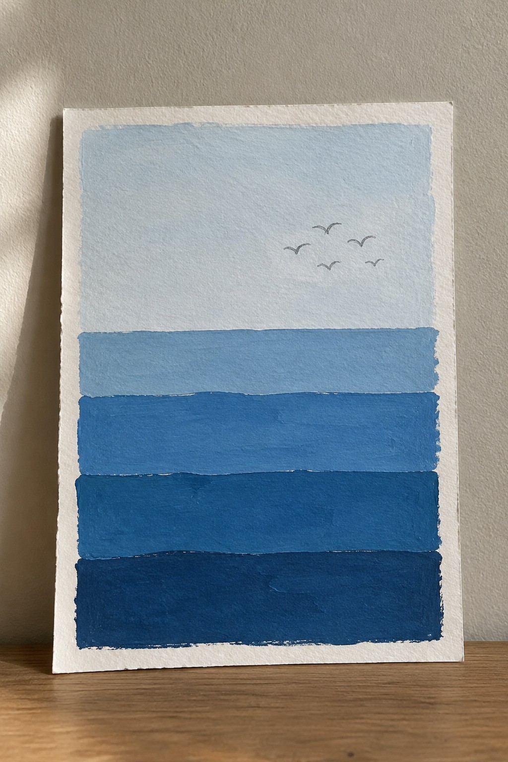 Watercolor seascape with layered blue stripes and five birds in pale sky.