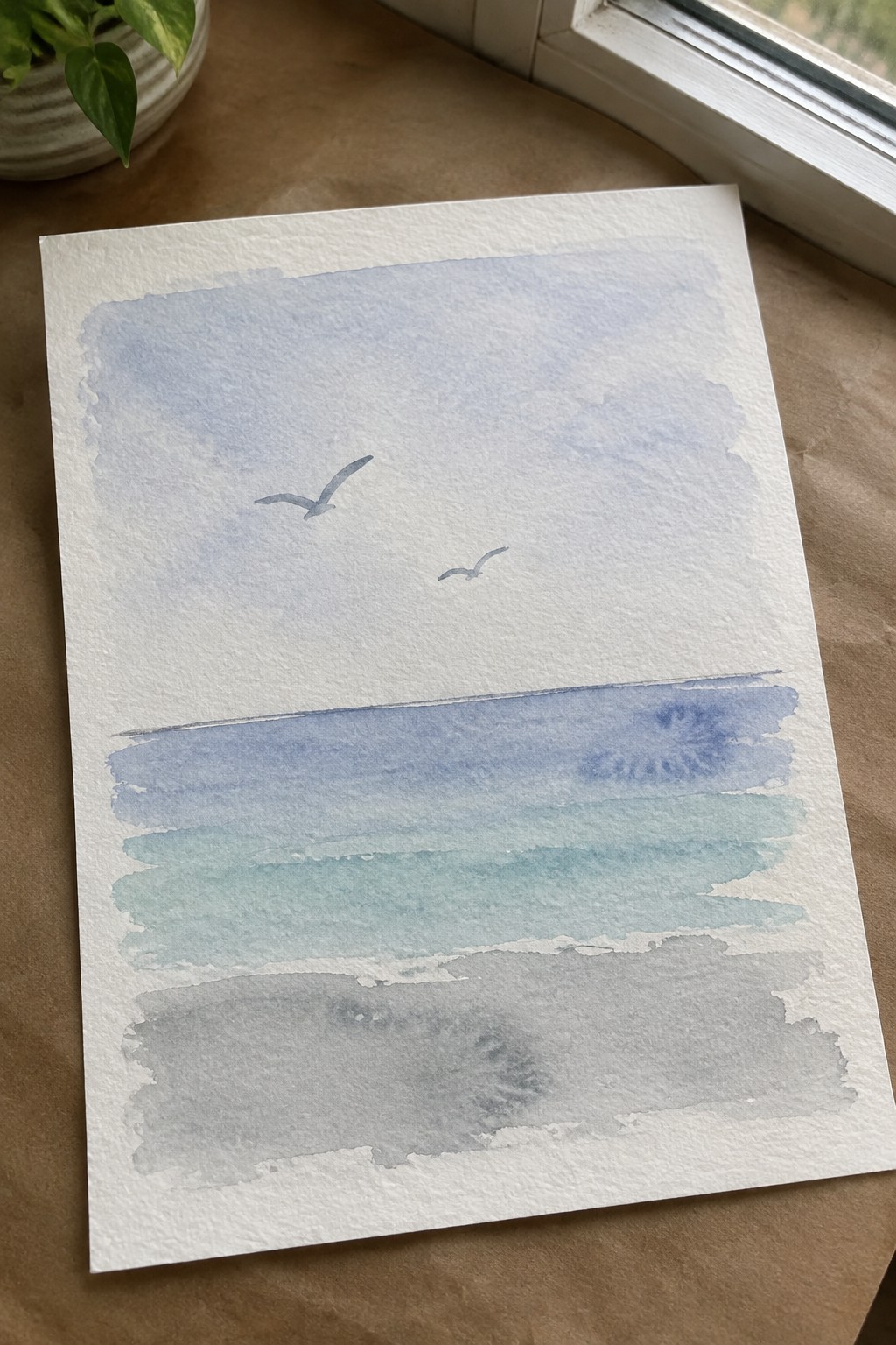 Watercolor seascape with two birds in pale blue sky above layered blue and gray waves