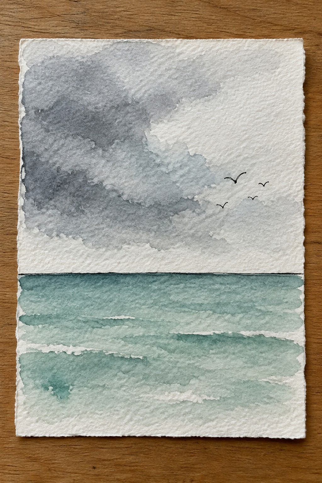 Watercolor seascape with gray clouds over teal waves and three flying birds
