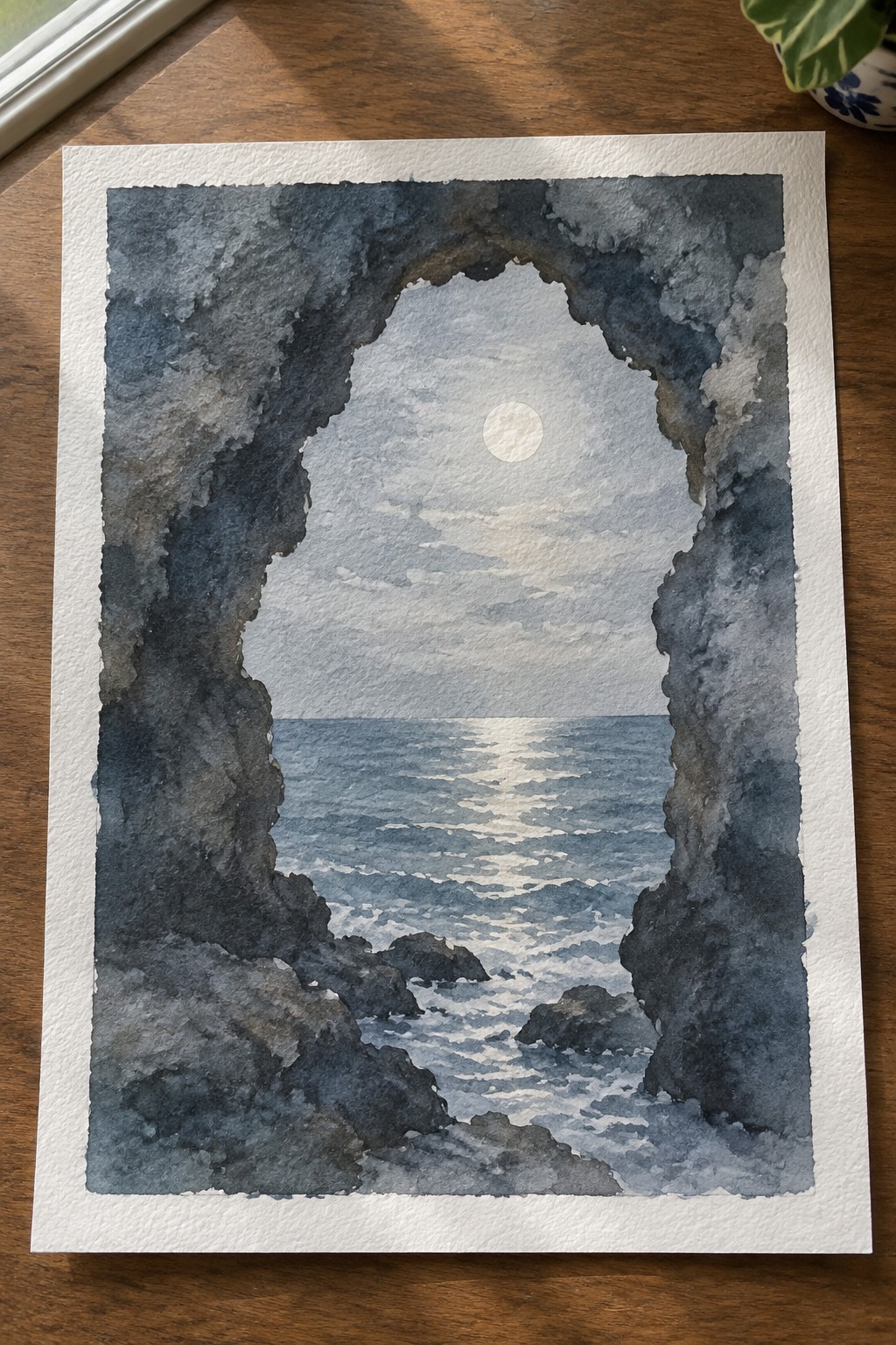 Watercolor seascape of moonlit ocean viewed through dark rocky archway