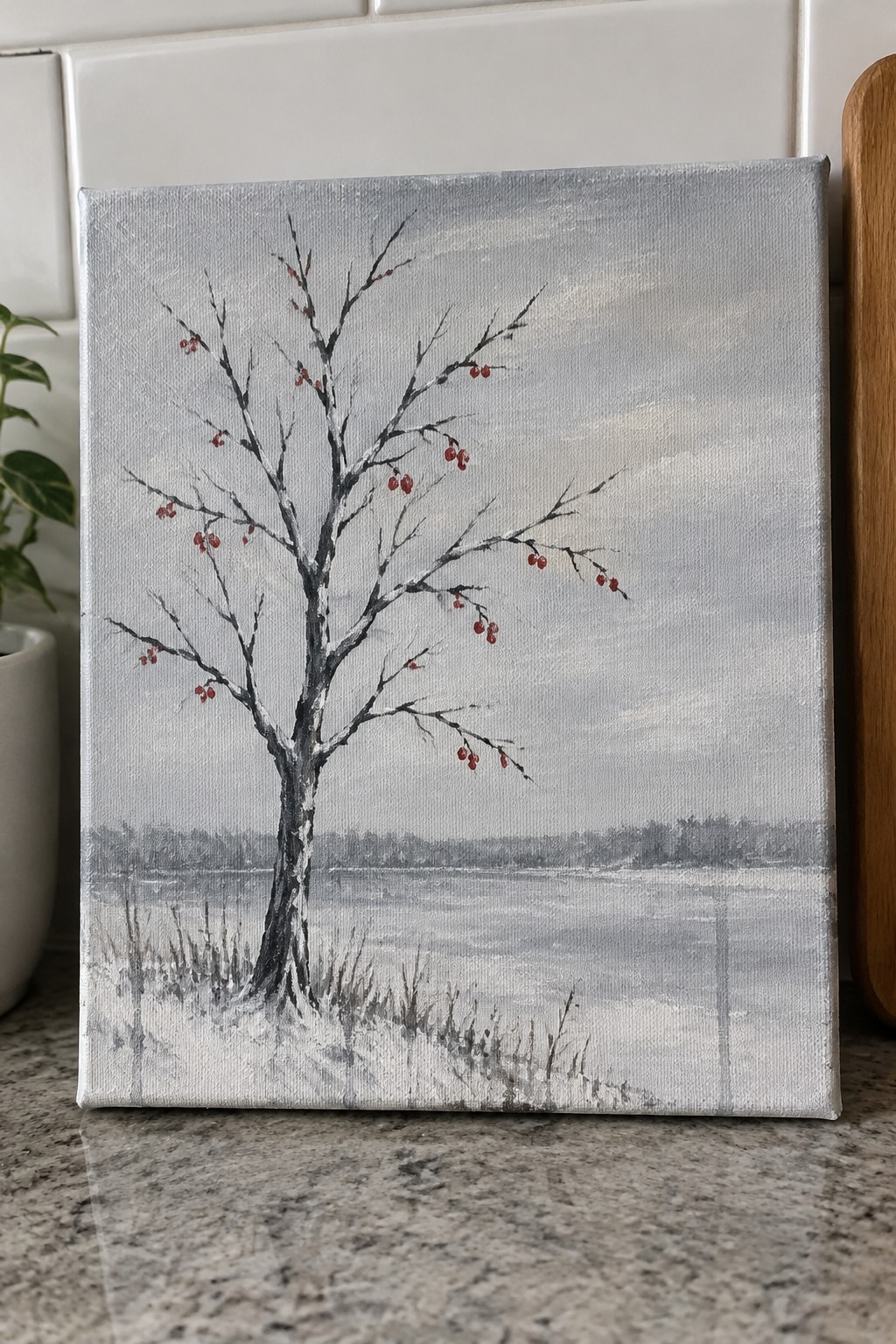 Canvas painting of bare tree with red berries by frozen snowy lake under gray sky