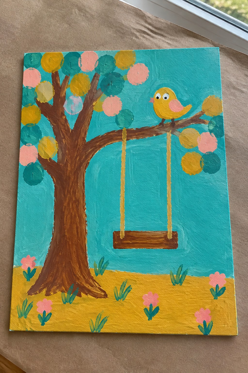 Colorful tree painting with yellow bird on branch above swing and pink flowers.