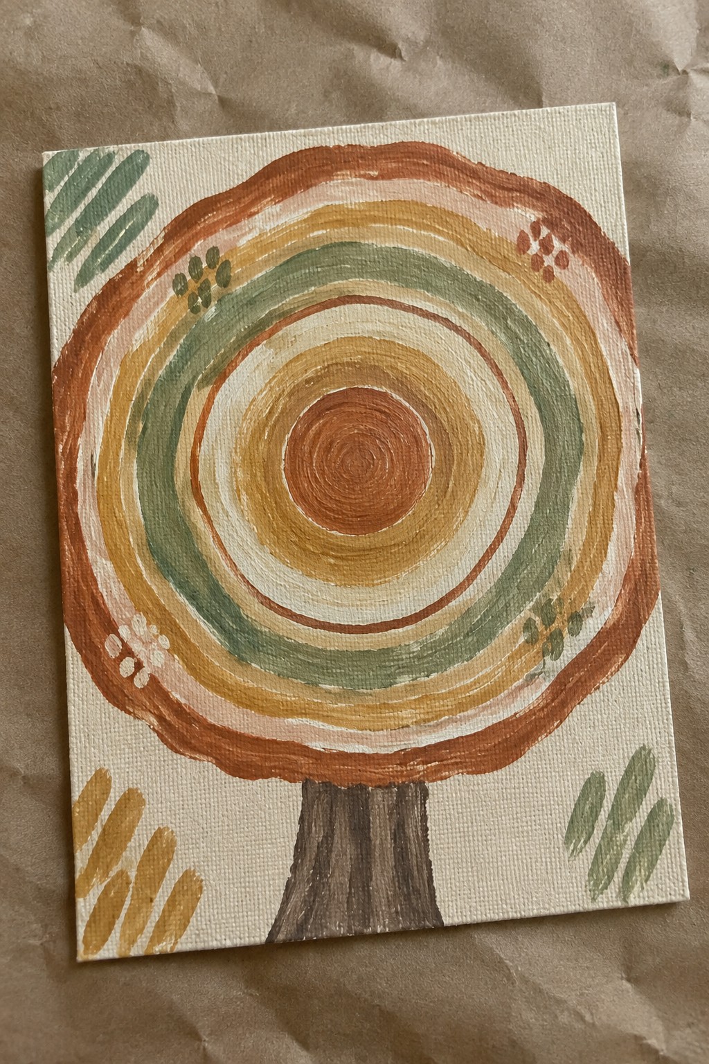 Abstract canvas painting of tree with brown trunk and colorful concentric rings.