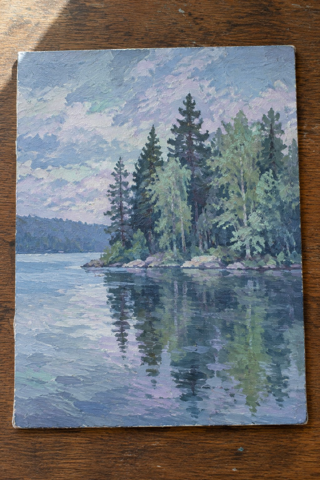 Serene lake reflecting pine trees and cloudy sky in impressionistic oil painting.