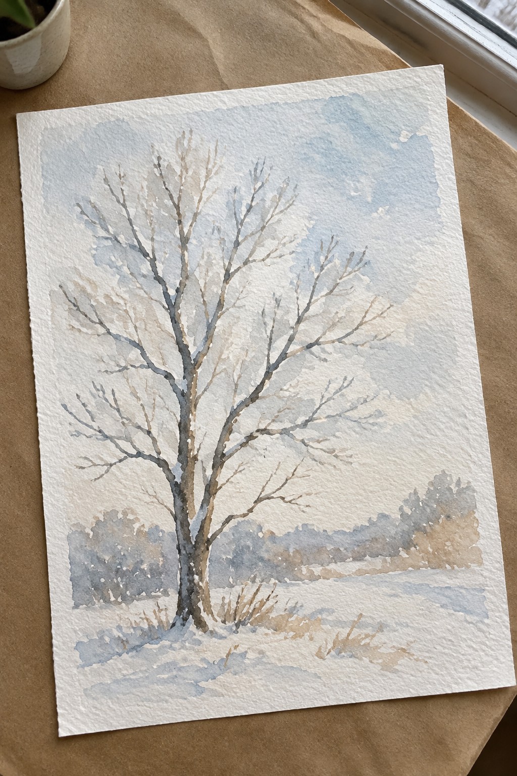 Watercolor of bare tree in snowy field under soft blue sky with distant bushes
