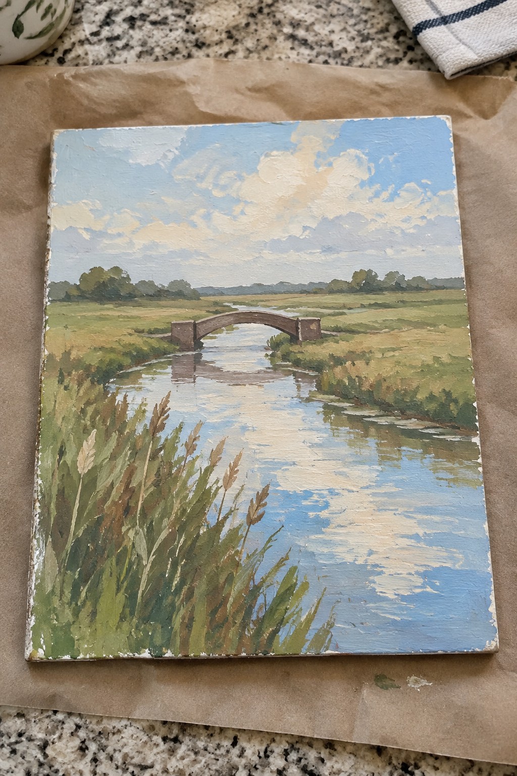 Landscape oil painting of stone bridge over river with foreground reeds under cloudy sky
