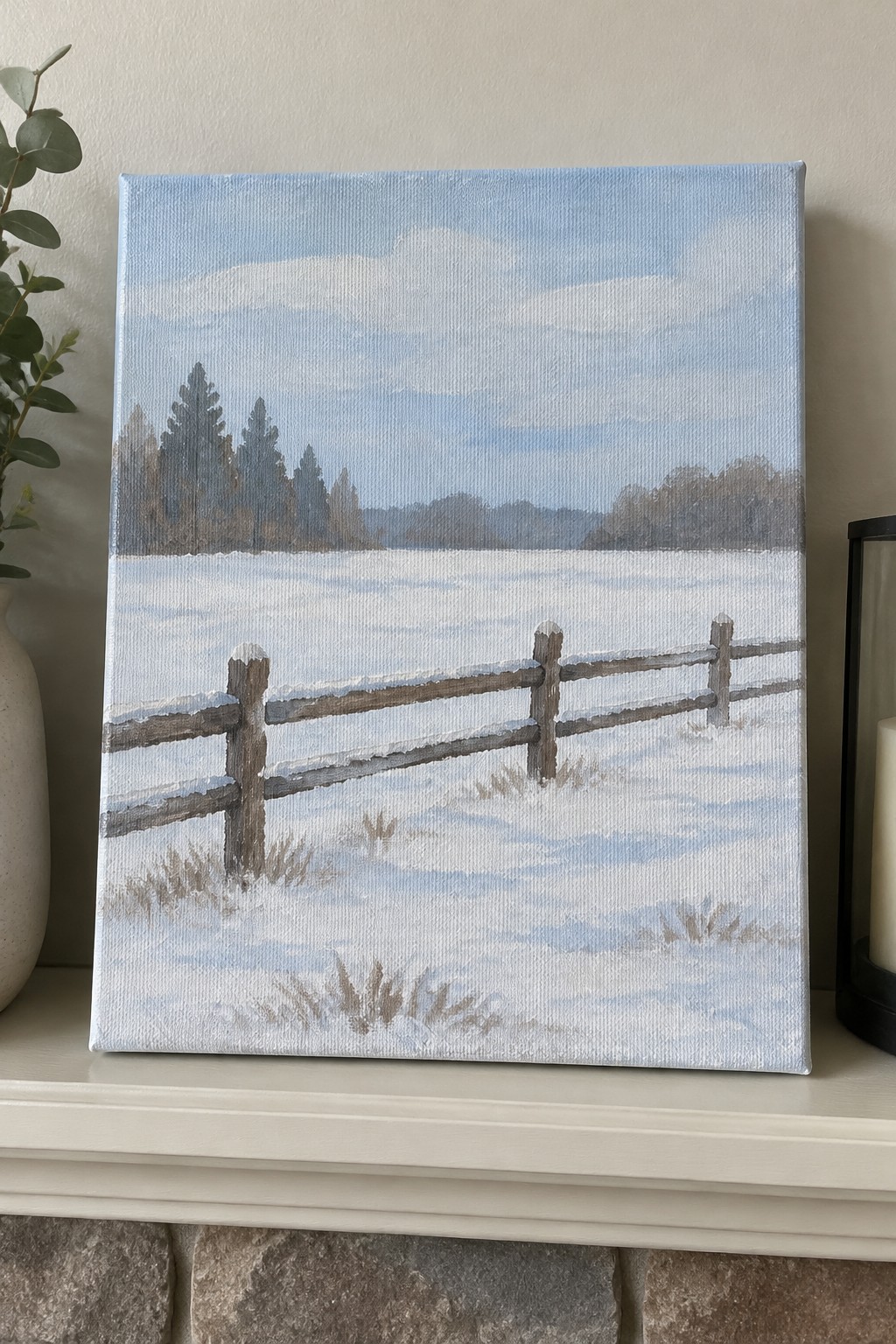 Painting of snowy field with wooden fence, distant trees under pale blue sky on mantel