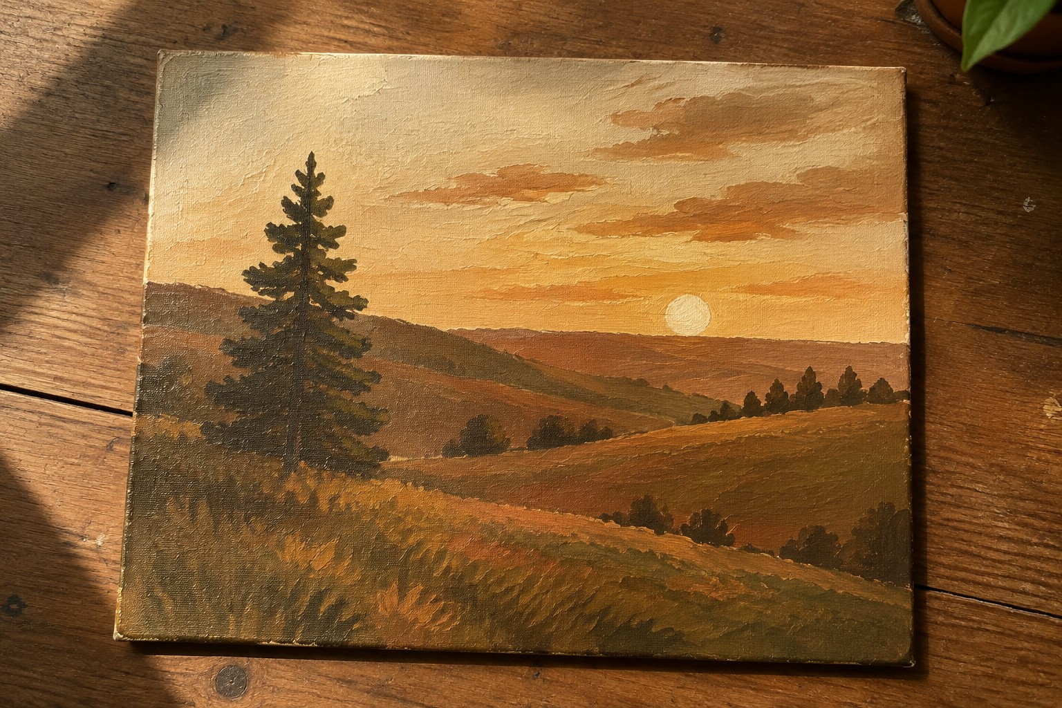 Sunset landscape painting with pine tree on wooden table beside plants and cloth