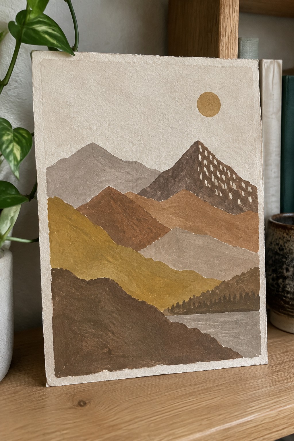 Layered mountain landscape in earthy browns, golds, and beiges with golden sun