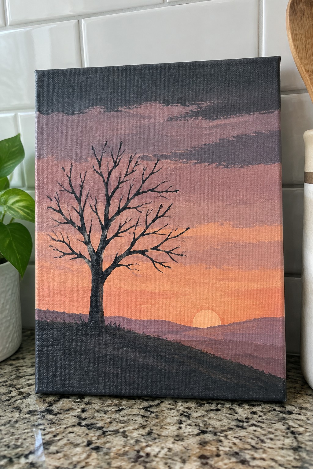 Painting of a bare tree silhouetted against a vibrant orange-pink sunset over hills.