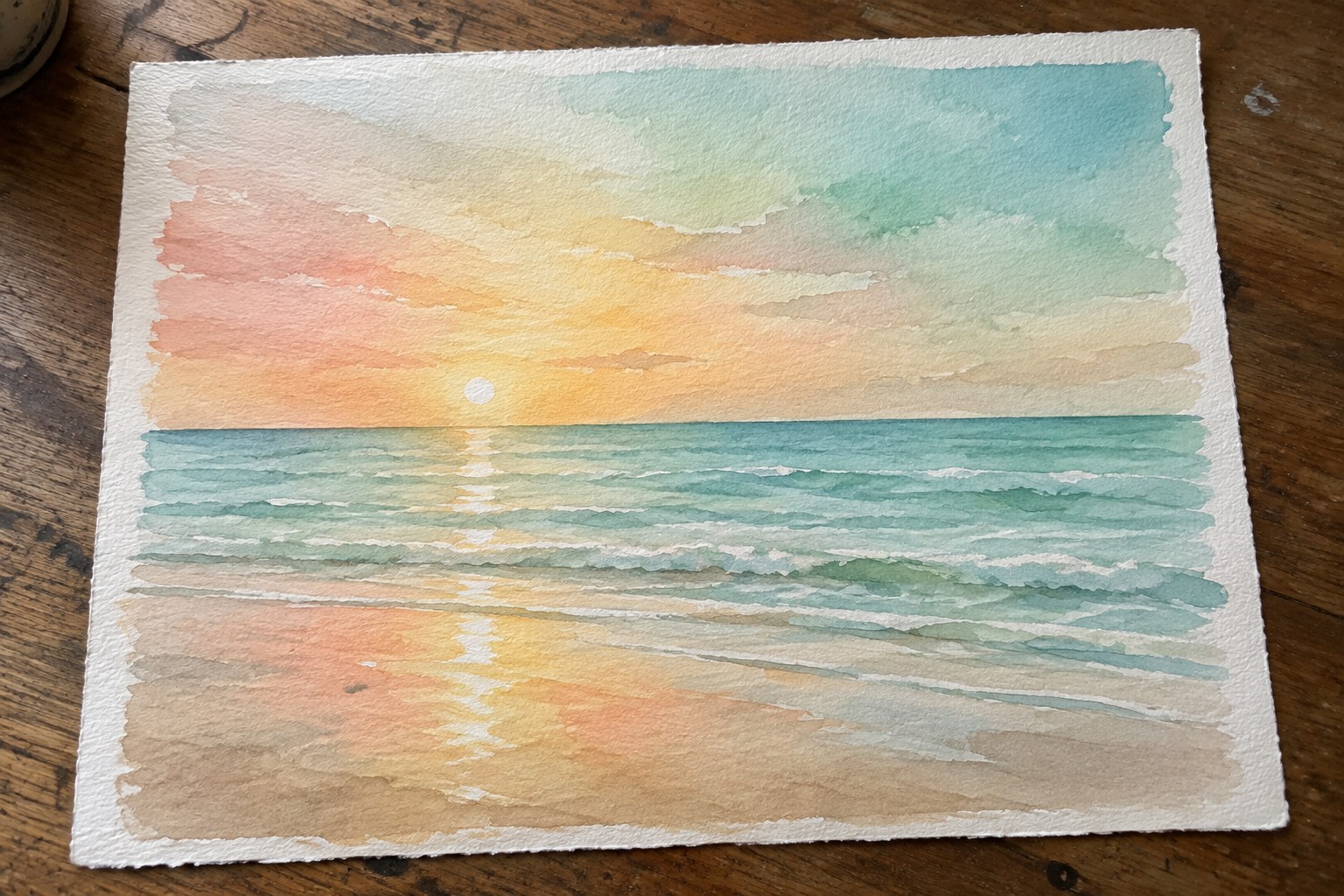 Watercolor painting of an ocean sunrise with the sun on the horizon, pink and yellow sky, layered blue-green waves, and a sandy beach with light reflections.
