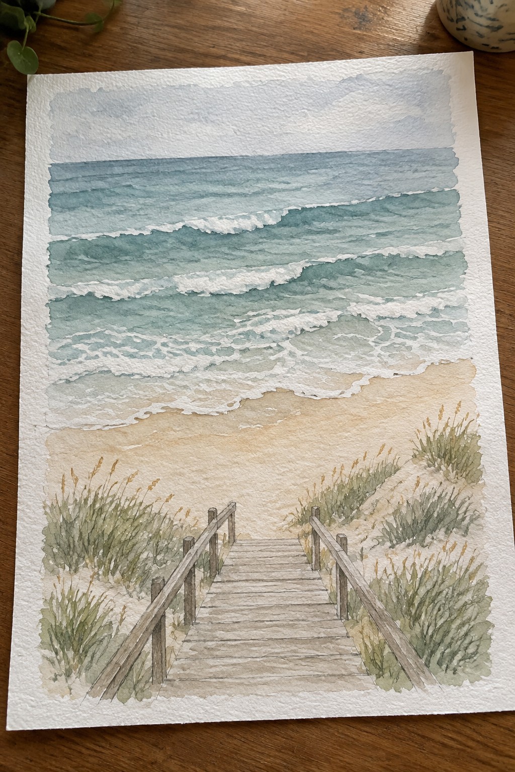 Watercolor of wooden boardwalk descending between grassy dunes to wavy blue ocean.
