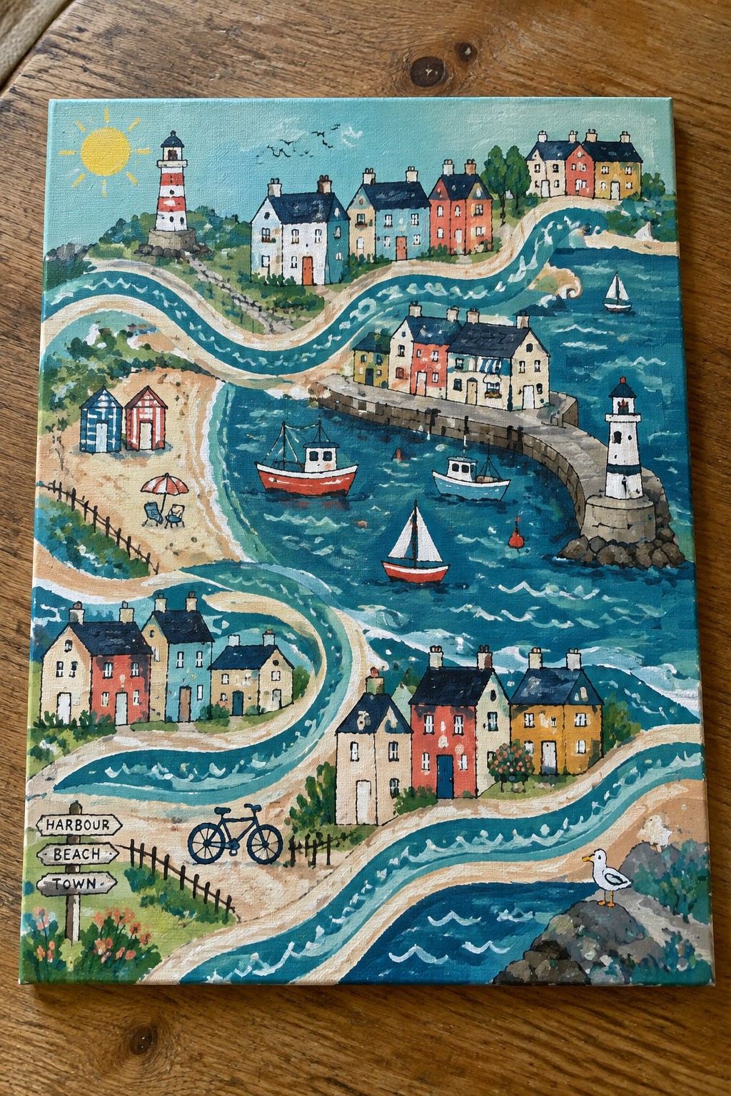 Colorful coastal village painting with striped lighthouses, boats, cottages, beach, and signpost.