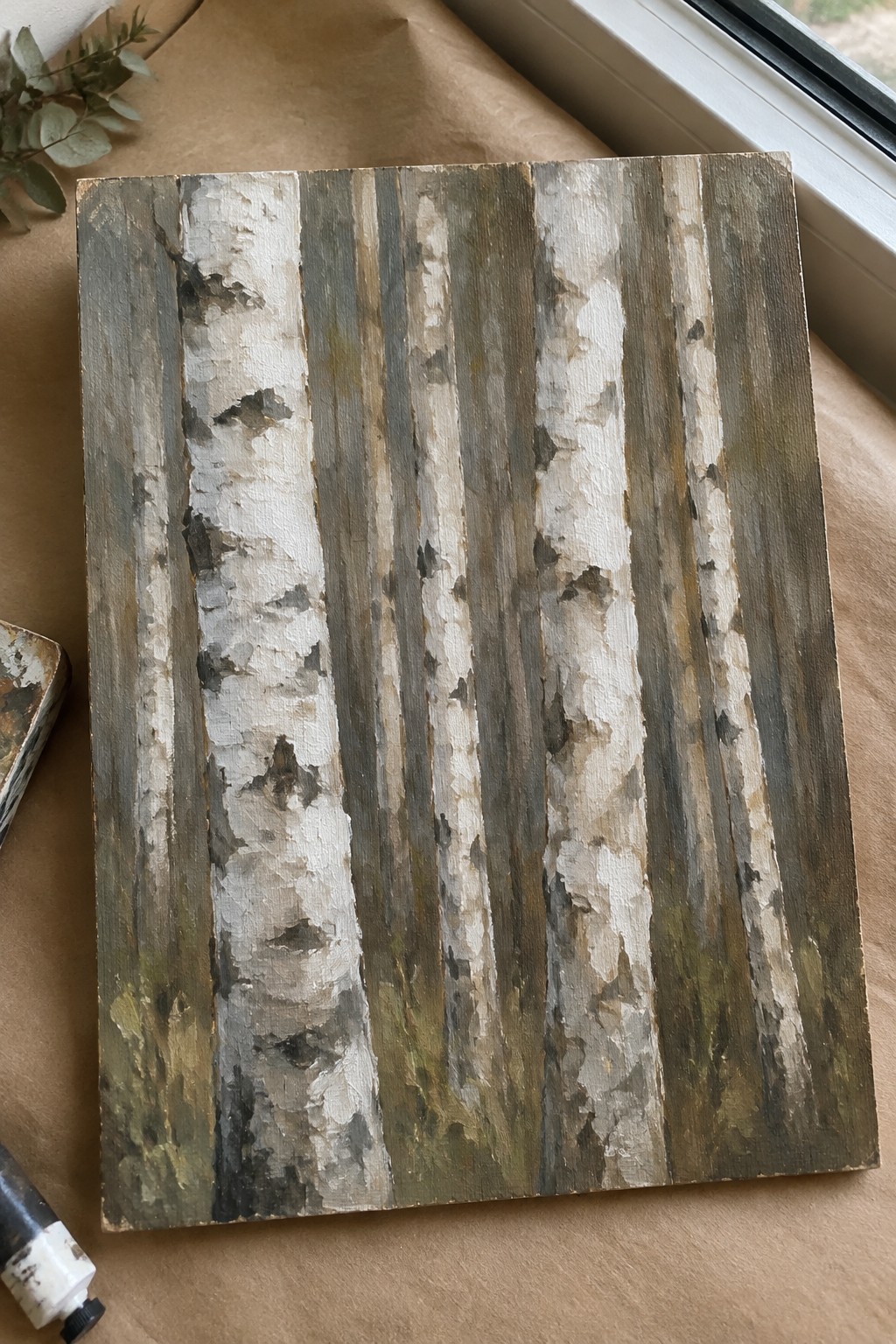 Textured birch tree trunks painting in white, gray, and brown on canvas with supplies.