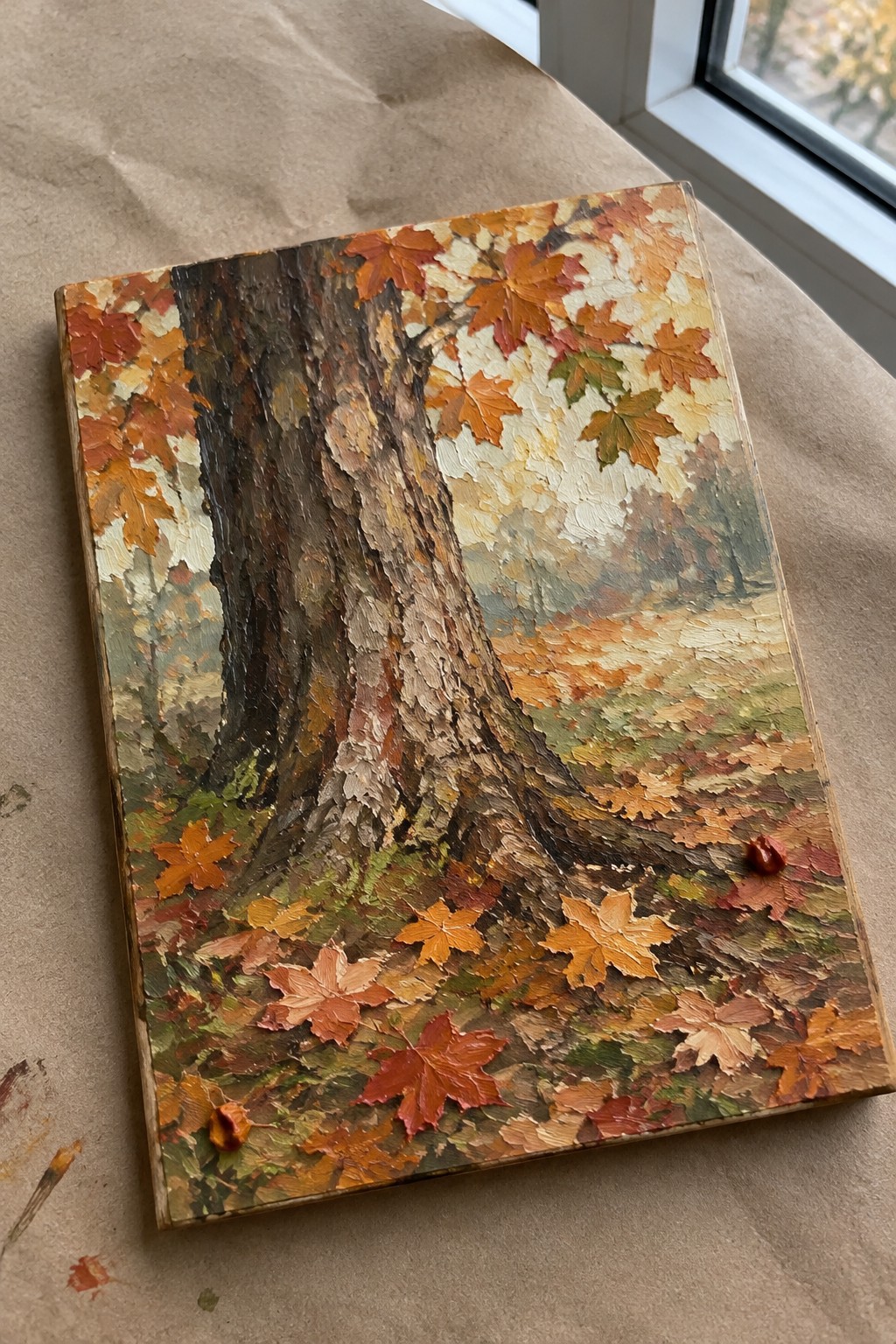 Thickly textured oil painting of autumn tree trunk with vibrant red and orange leaves.