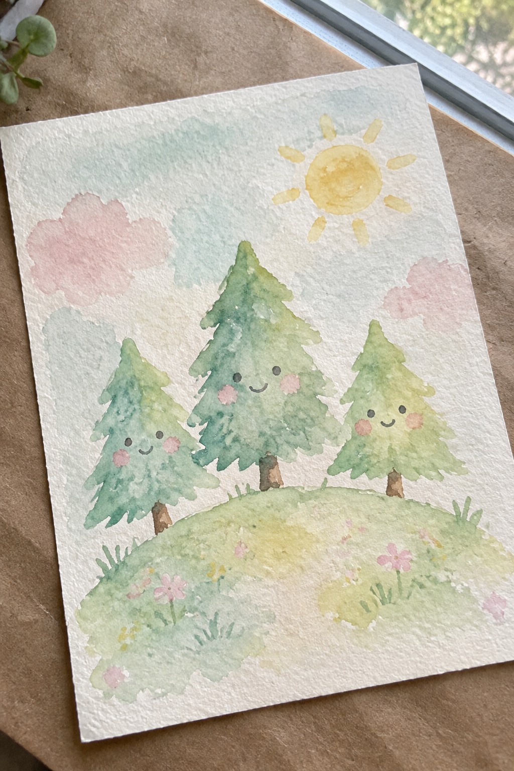 Watercolor painting of three smiling pine trees on a flowery hill under a yellow sun with pink clouds.