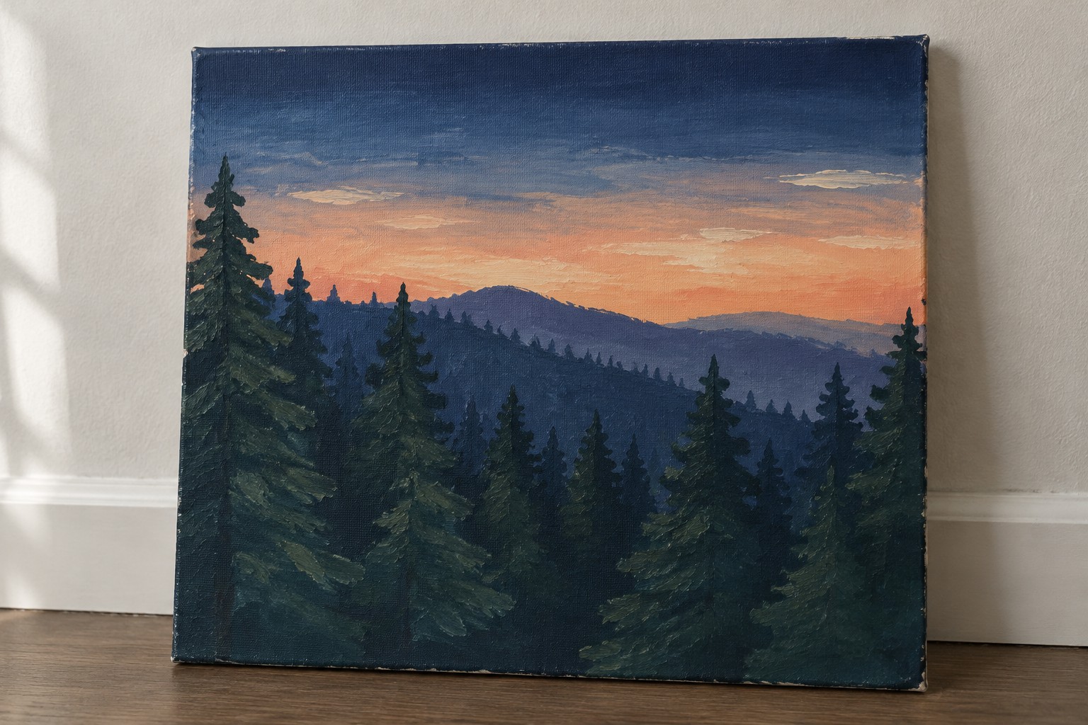 A rectangular canvas painting shows a dense pine forest silhouette in dark green and blue tones against a sunset sky that gradients from orange near the horizon to deep blue above, with layered mountains in the distance.