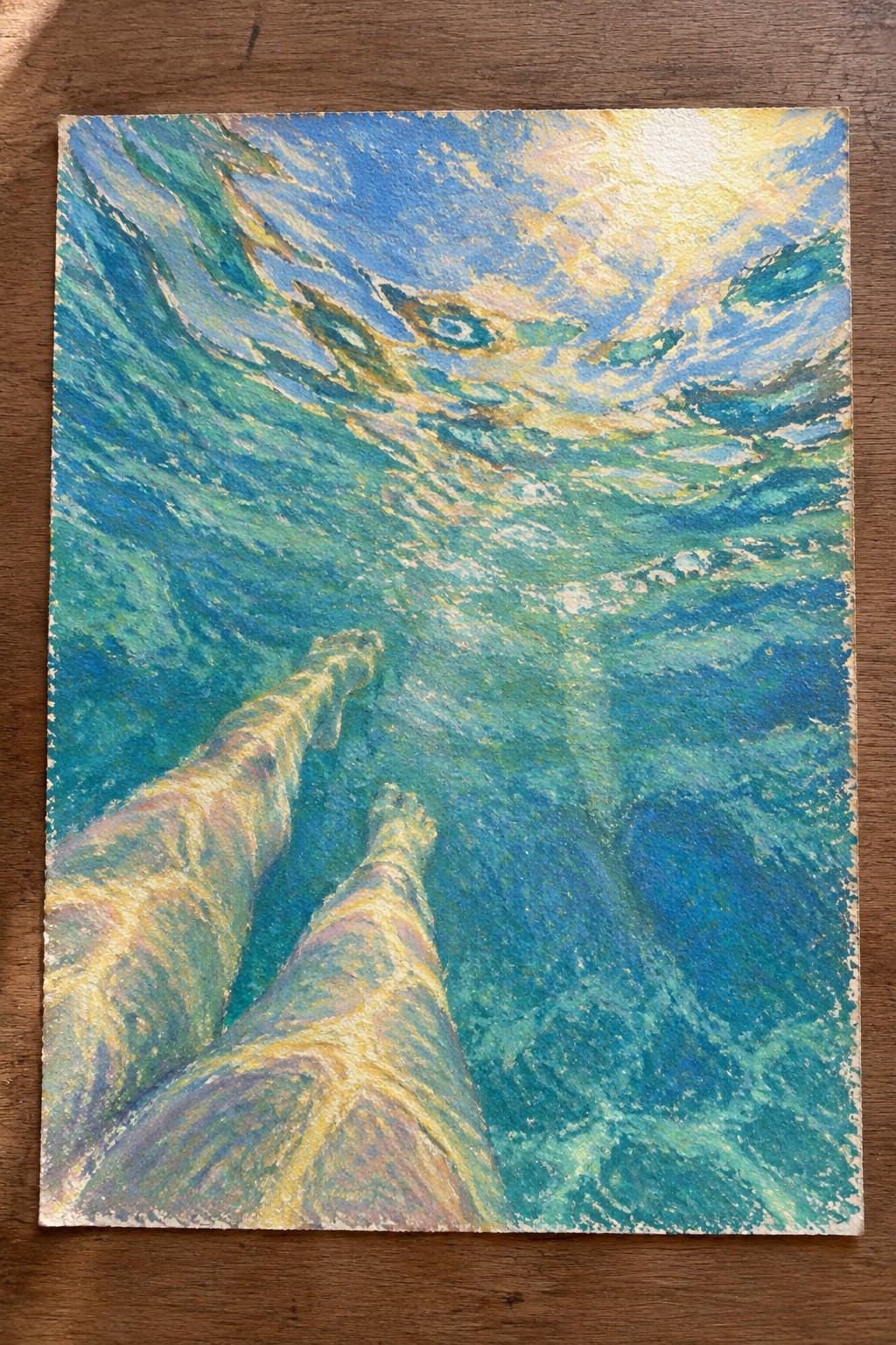 Underwater view of legs in swirling blue-green waves with sunlight overhead