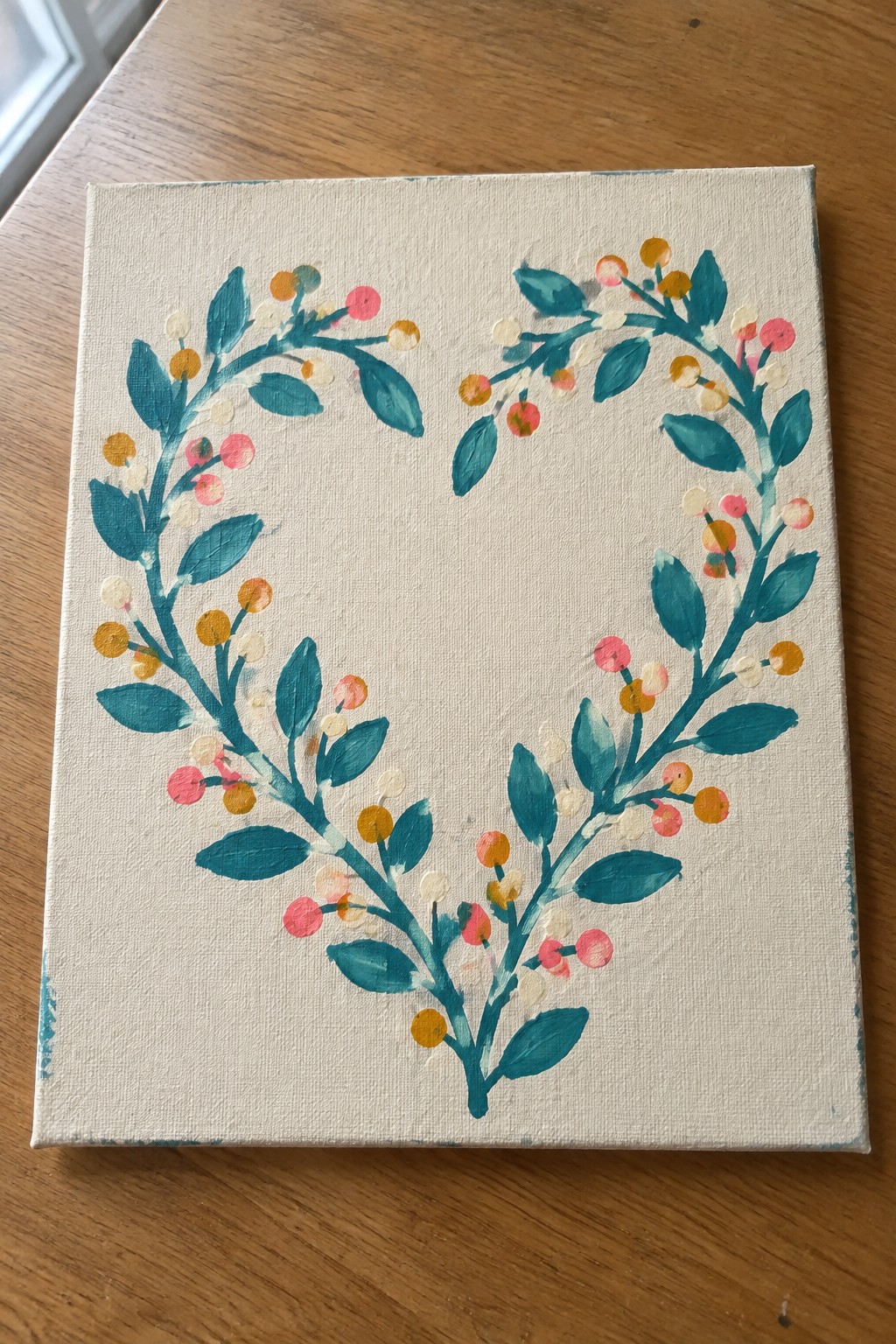A square canvas shows a heart-shaped wreath painted with teal branches, green leaves, and clusters of small berries in pink, yellow, and white.