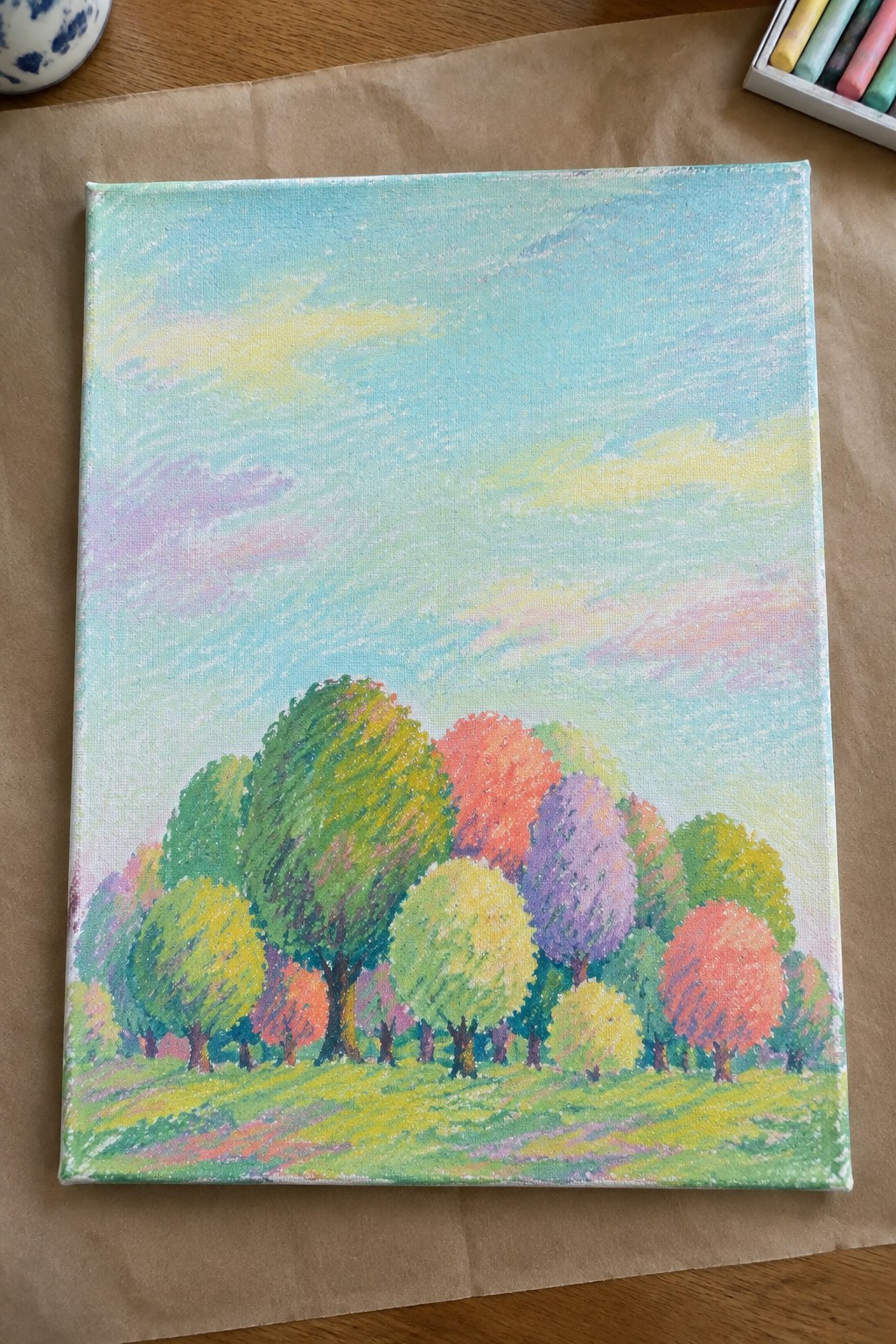 Colorful rounded trees in green, red, purple, and yellow on a grassy field under pastel sky