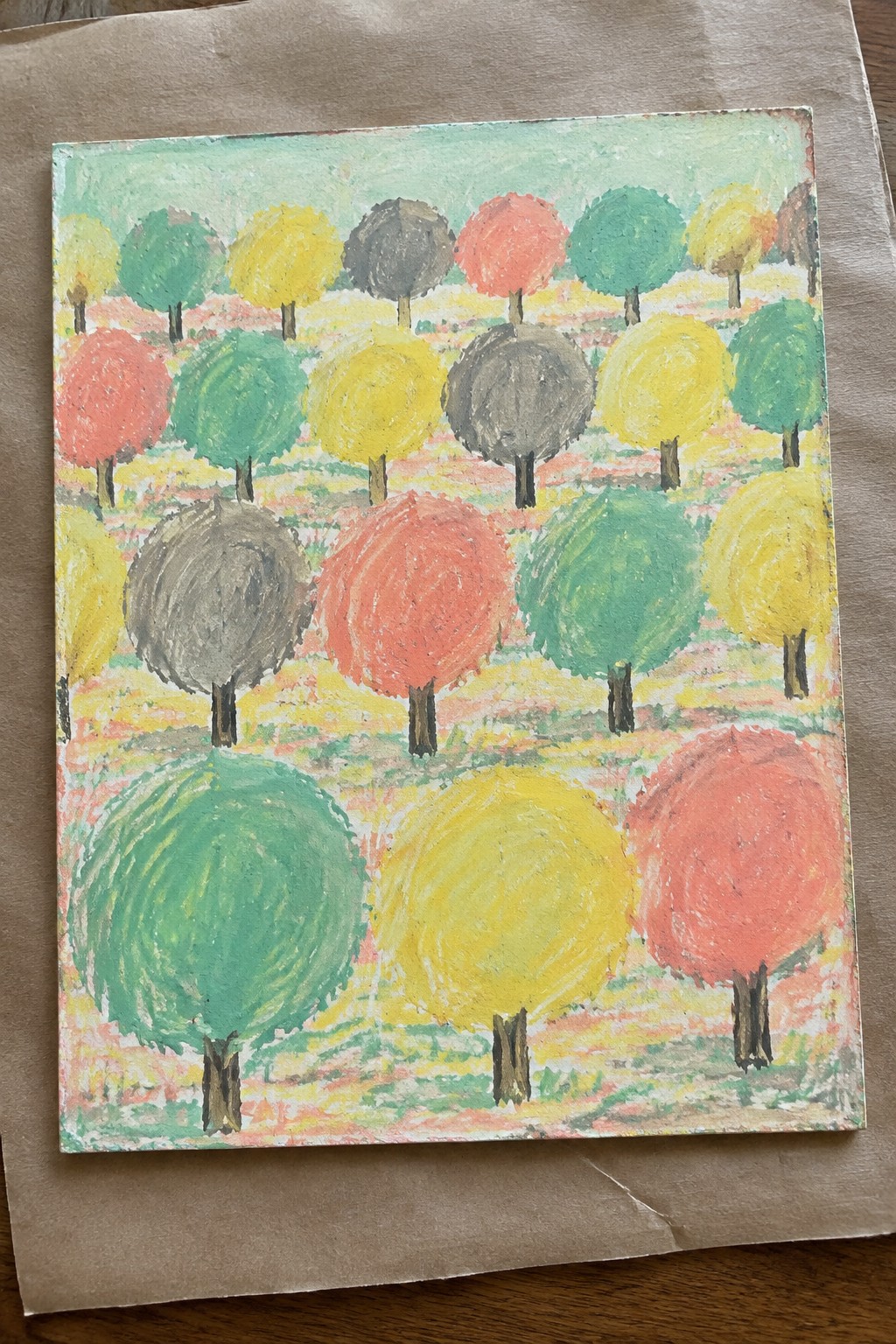 Rows of vibrant red, yellow, green, and gray round trees with brown trunks on colorful ground.