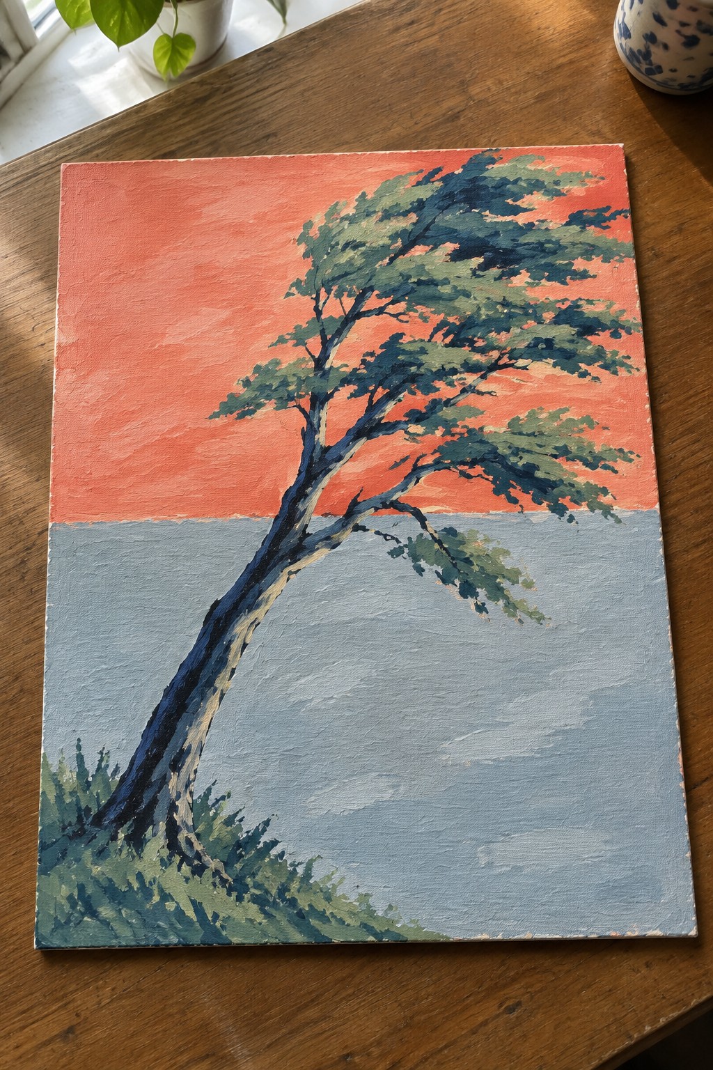 Vibrant painting of windswept tree with blue trunk against red-orange sky over blue water