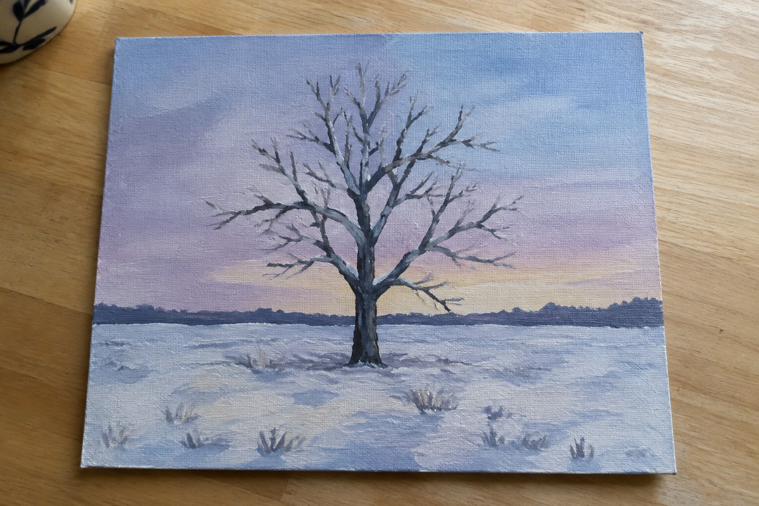 Painting of leafless tree in snowy field under purple and orange dusk sky