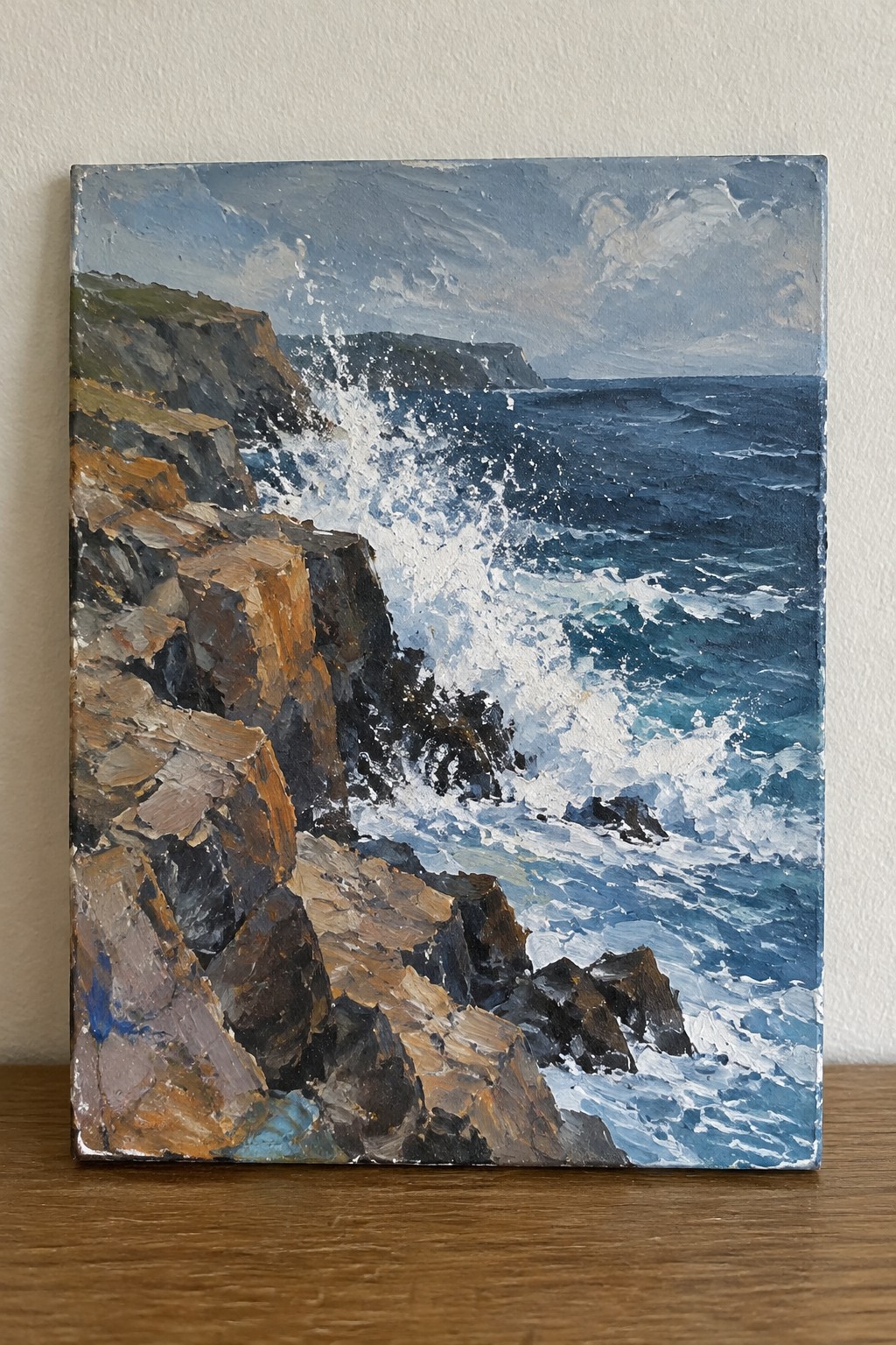 Oil painting of waves crashing on brown rocky cliffs under cloudy sky