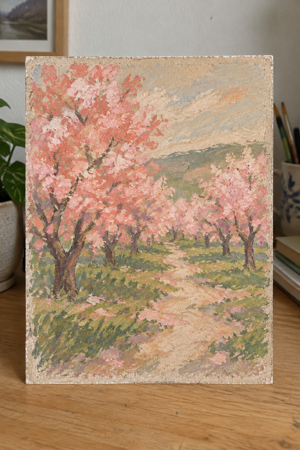 Impressionistic painting of pink cherry trees lining a winding path through green hills.