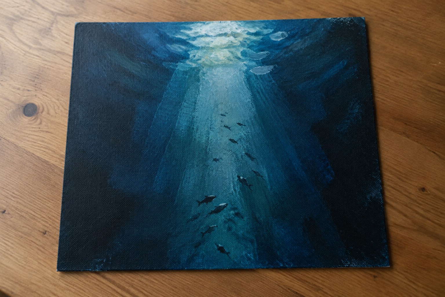 Blue underwater painting of fish swimming through sunlit ocean light rays on wood