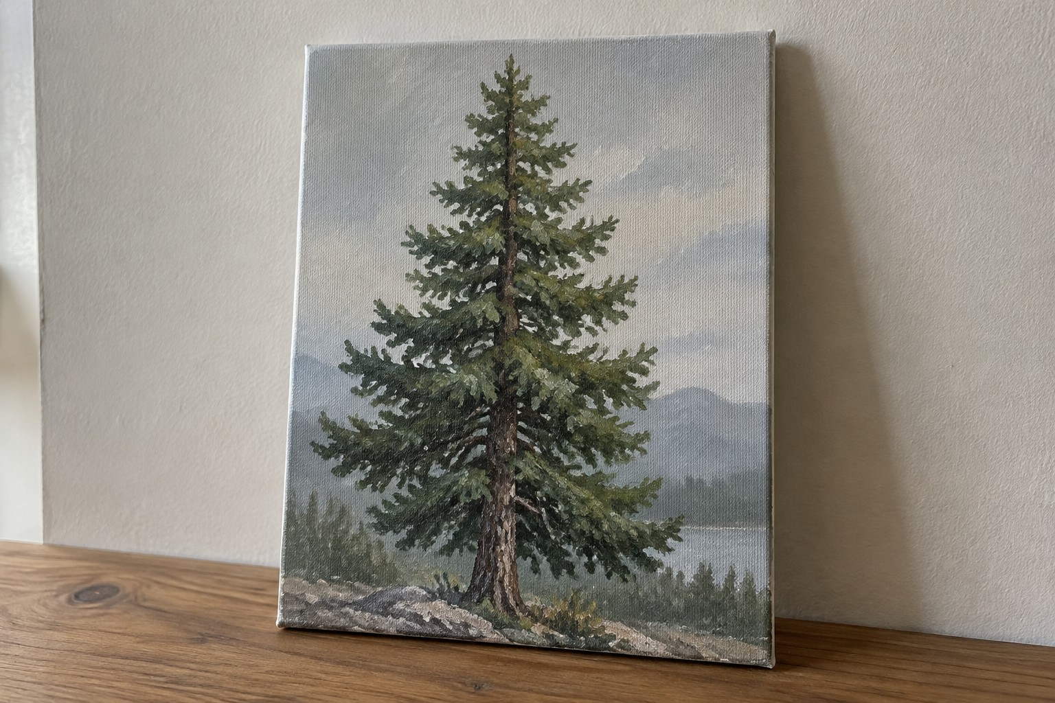 Tall evergreen tree painting on canvas atop wooden surface with plant and books