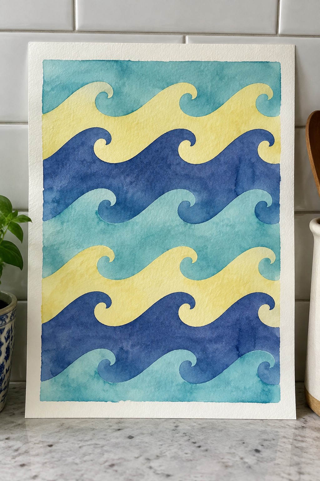Watercolor painting of layered blue, teal, and yellow wave patterns on counter