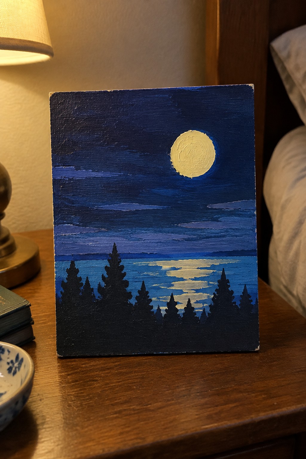 Moonlit night painting with full moon reflecting on lake amid silhouetted pine trees