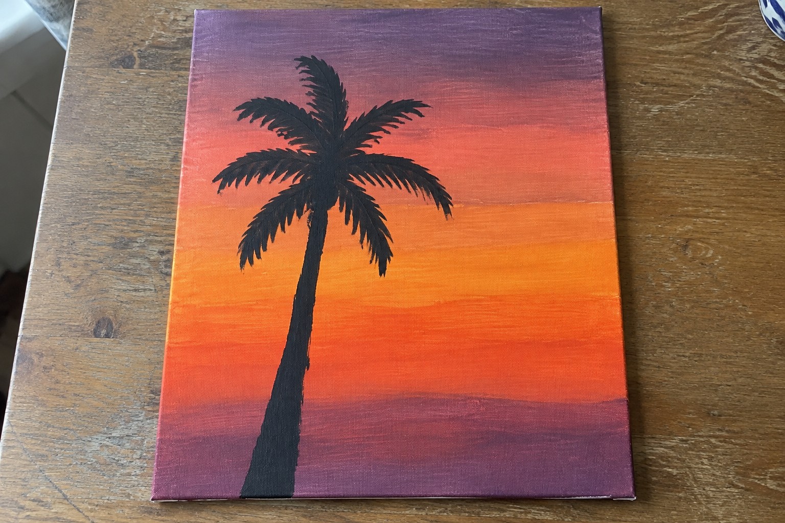 Silhouetted palm tree against vibrant orange purple red sunset on canvas