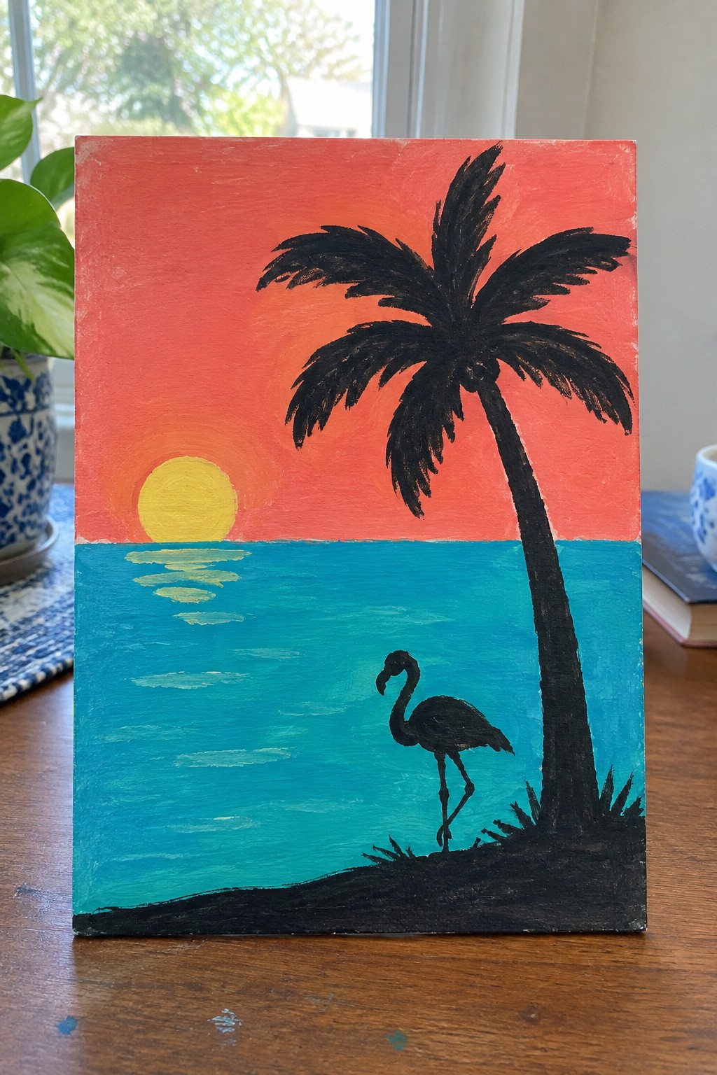 Vibrant sunset painting with red-orange sky, yellow sun, turquoise sea, palm tree and flamingo.