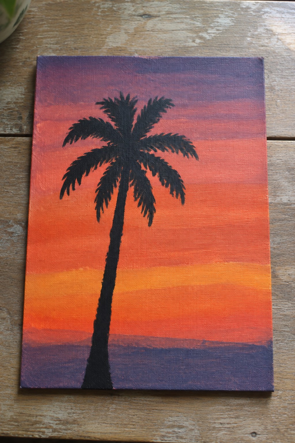 Silhouetted palm tree against vibrant orange purple red sunset on canvas