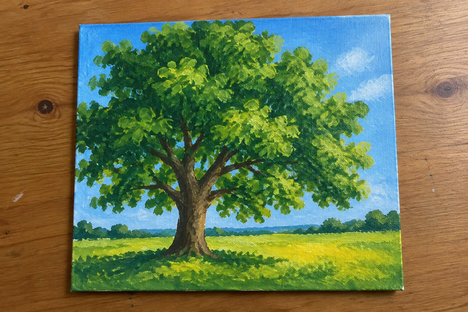 Landscape painting of large leafy tree in sunny green field under blue sky