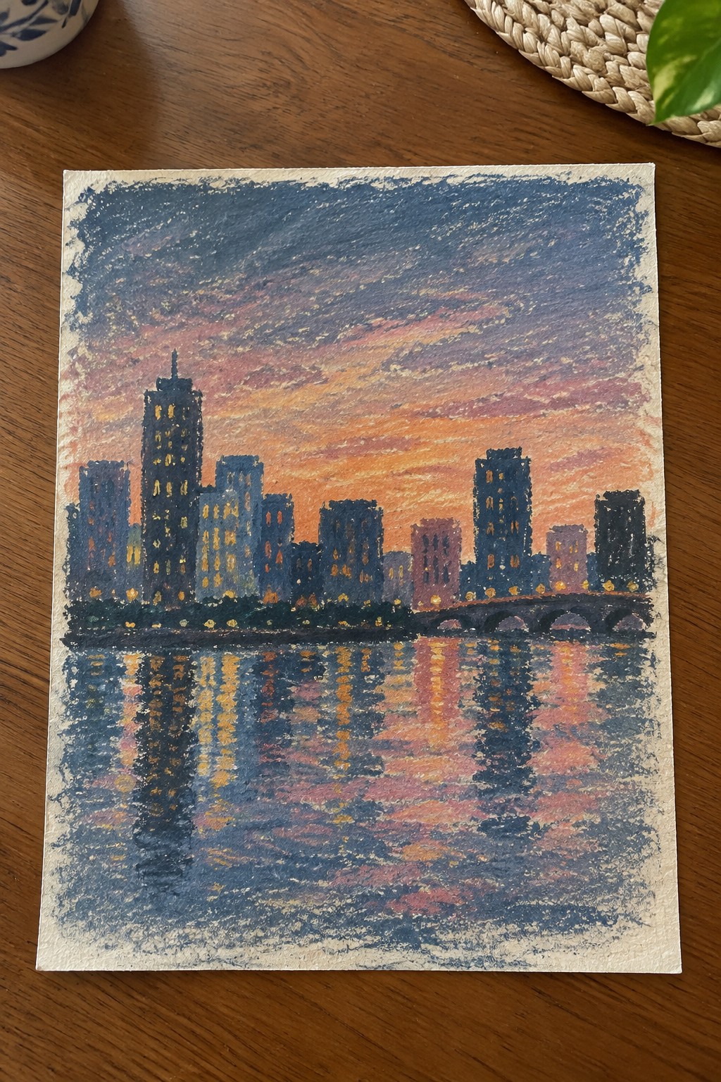 Colorful pastel cityscape at sunset with illuminated skyscrapers reflected in water