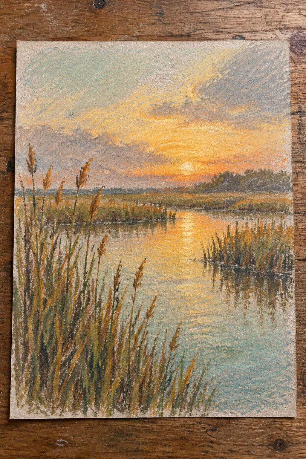 Pastel sunset over marsh with golden sun reflection and tall foreground reeds