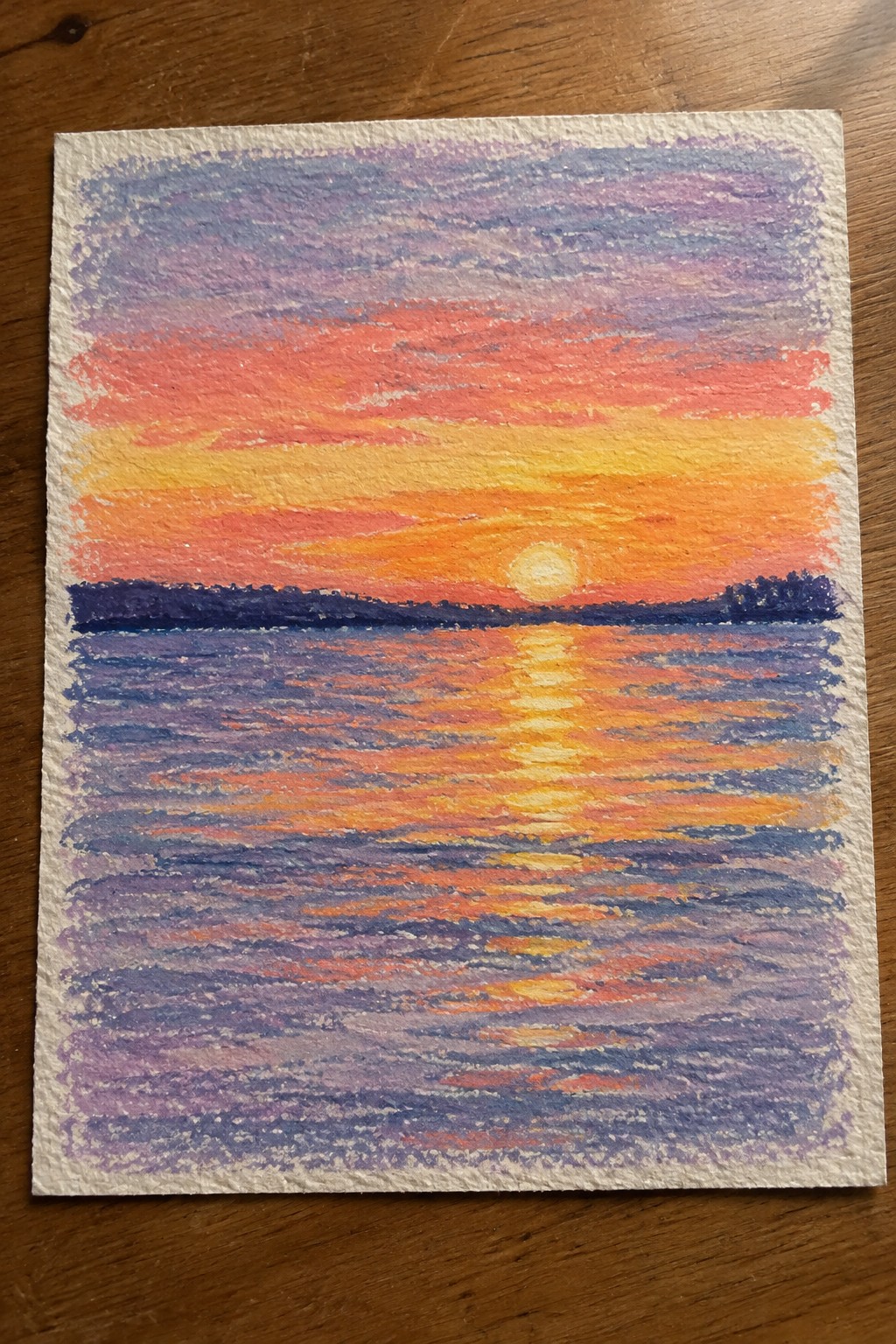 Vibrant pastel sunset over water with orange sky, yellow sun, and reflections