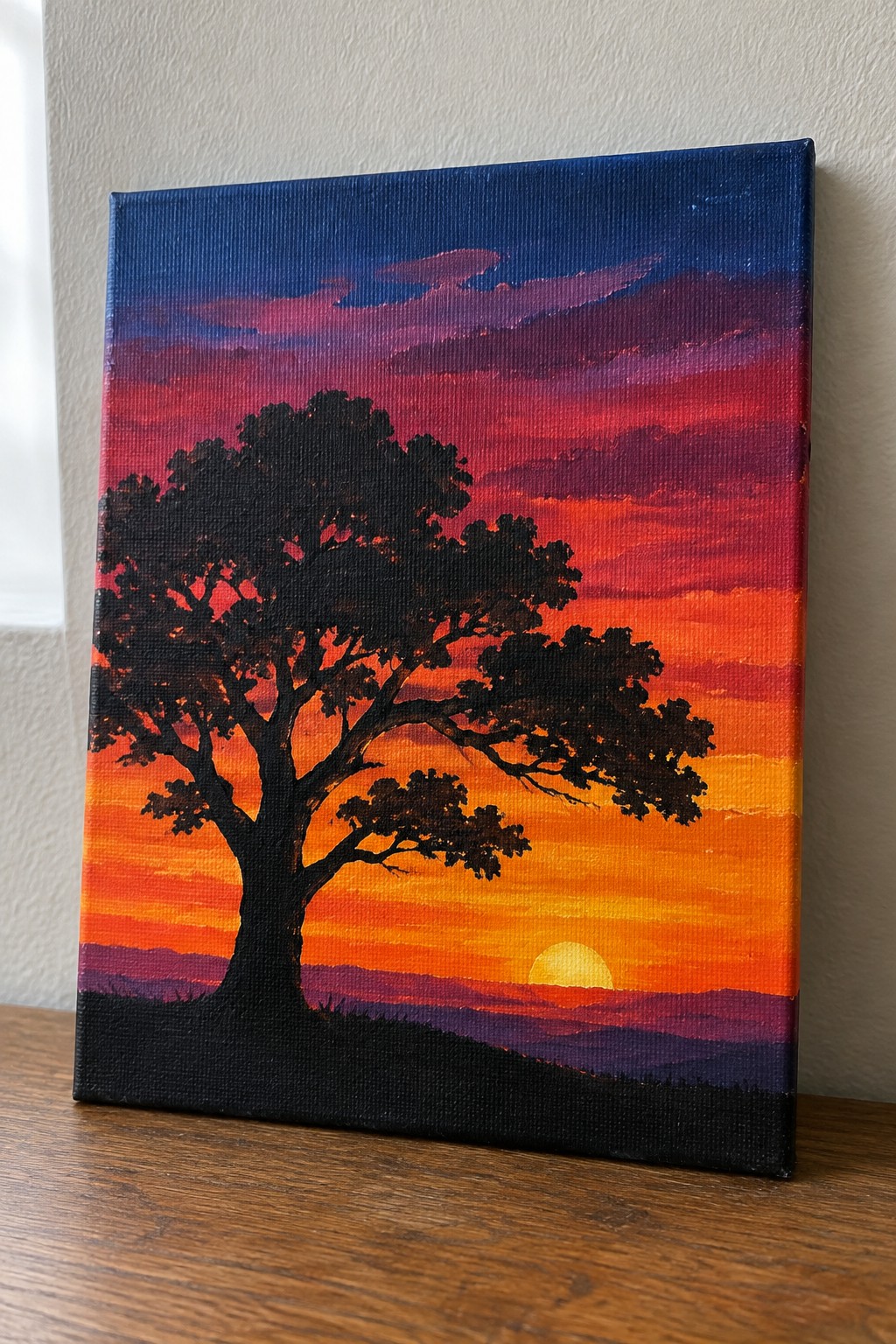 Silhouetted tree against vibrant red-orange sunset sky with yellow sun on canvas