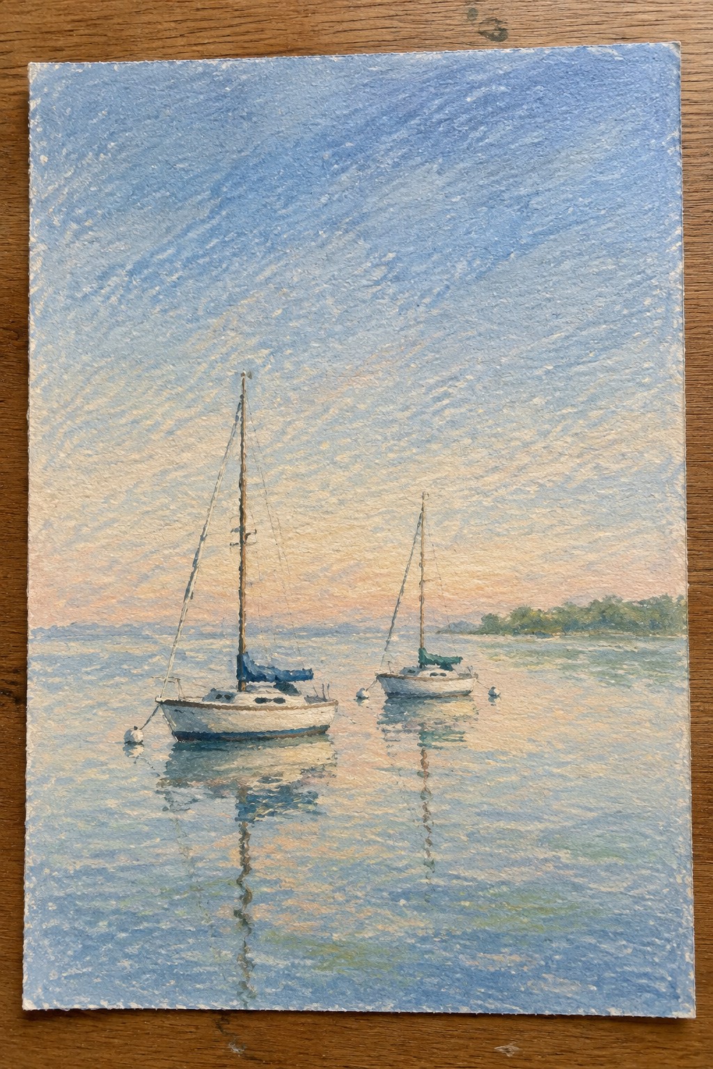 Two sailboats moored on calm water reflecting a blue-orange sunset sky.