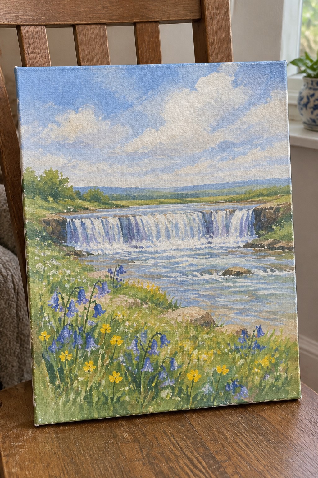 Landscape painting of waterfall with blue wildflowers on wooden chair