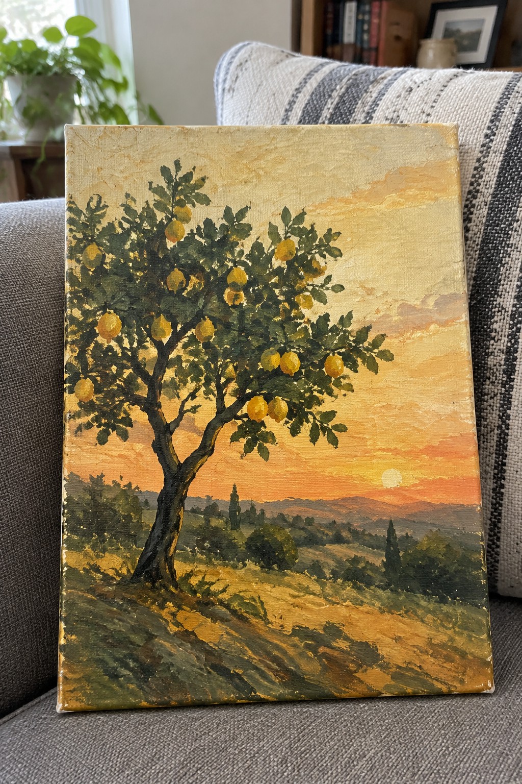 Oil painting of lemon tree with yellow fruit at sunset on canvas against couch
