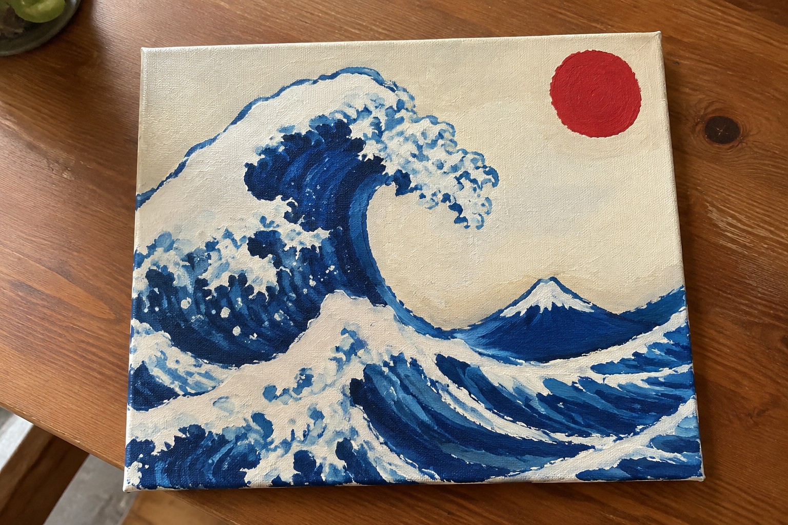 Canvas painting of curling blue wave with white foam and red sun
