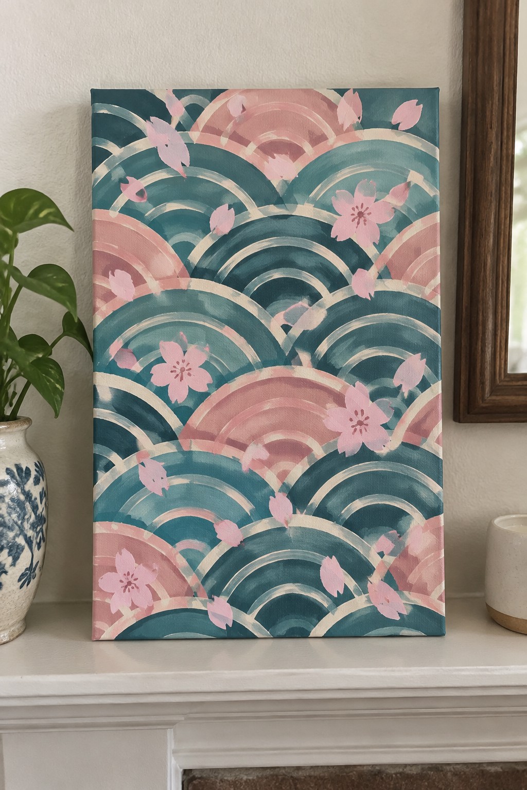 Teal and pink wave painting with cherry blossoms on white mantel beside potted plant
