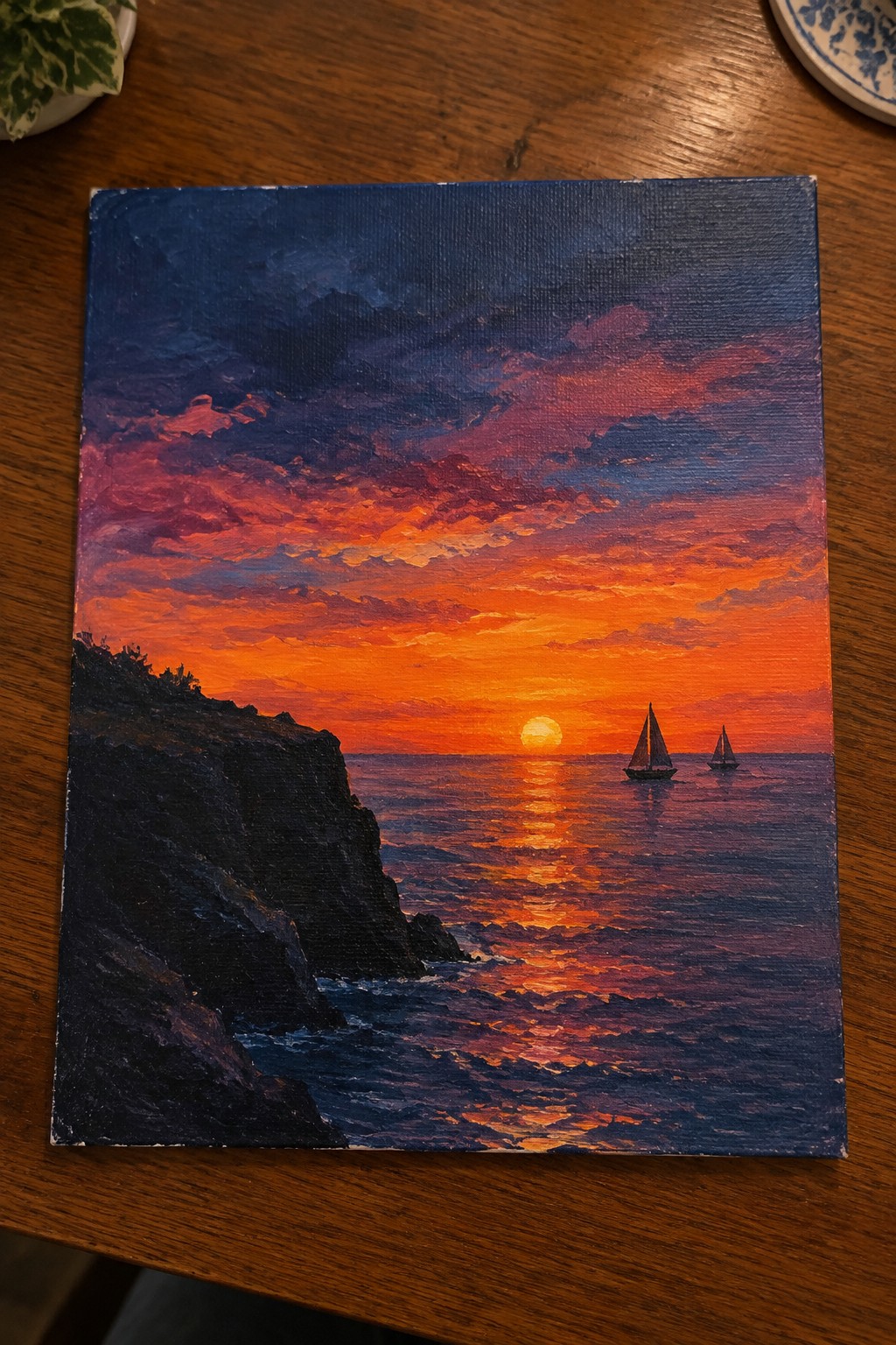 Vibrant oil painting of ocean sunset with rocky cliffs and two sailboats.